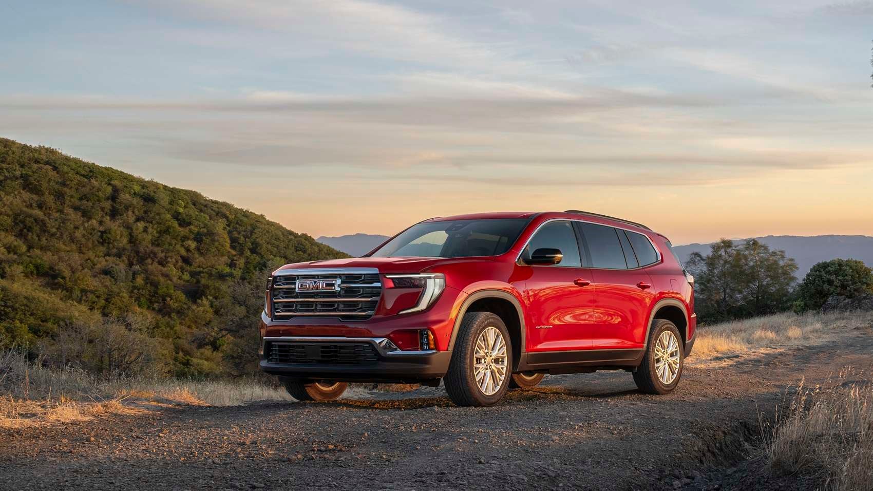 Red GMC Acadia parked on a hiking trail during sunset